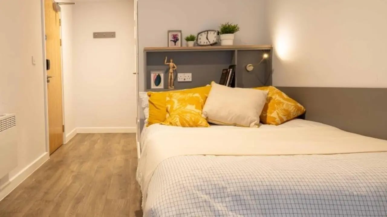 Bed with yellow pillows and artwork above bedroom at iQ Nelson Court in Nottingham Student Accommodation
