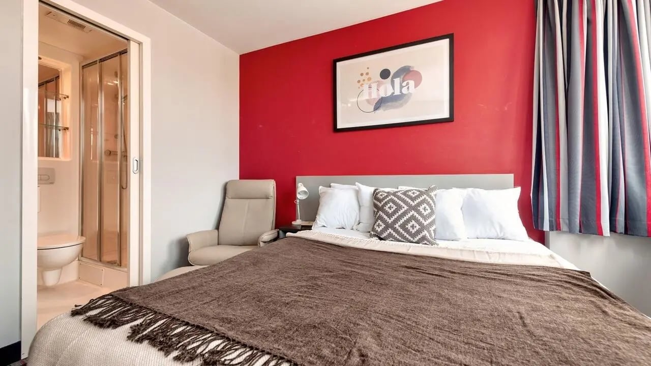 Bed shower chair artwork curtains bedroom at Collegiate Castle Street in Cambridge Student Accommodation
