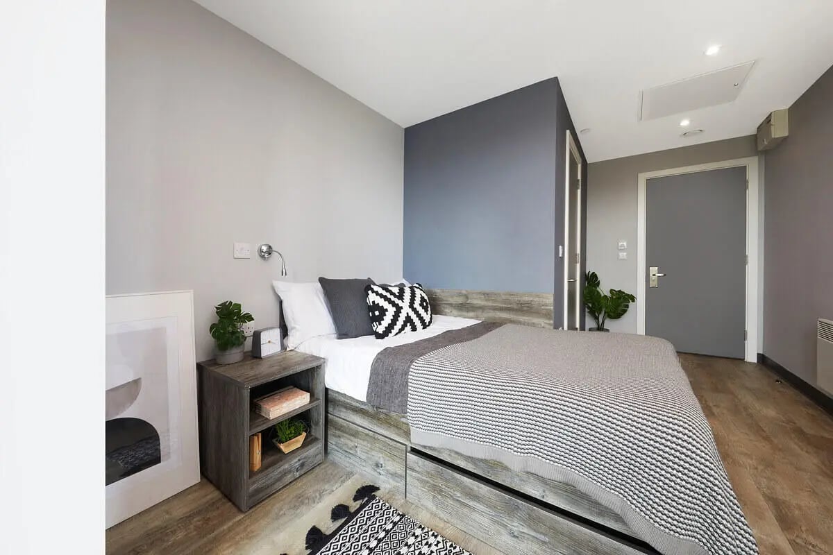 Bed with grey blanket nightstand framed art bedroom at Collegiate Crown Place Norwich in Norwich Student Accommodation
