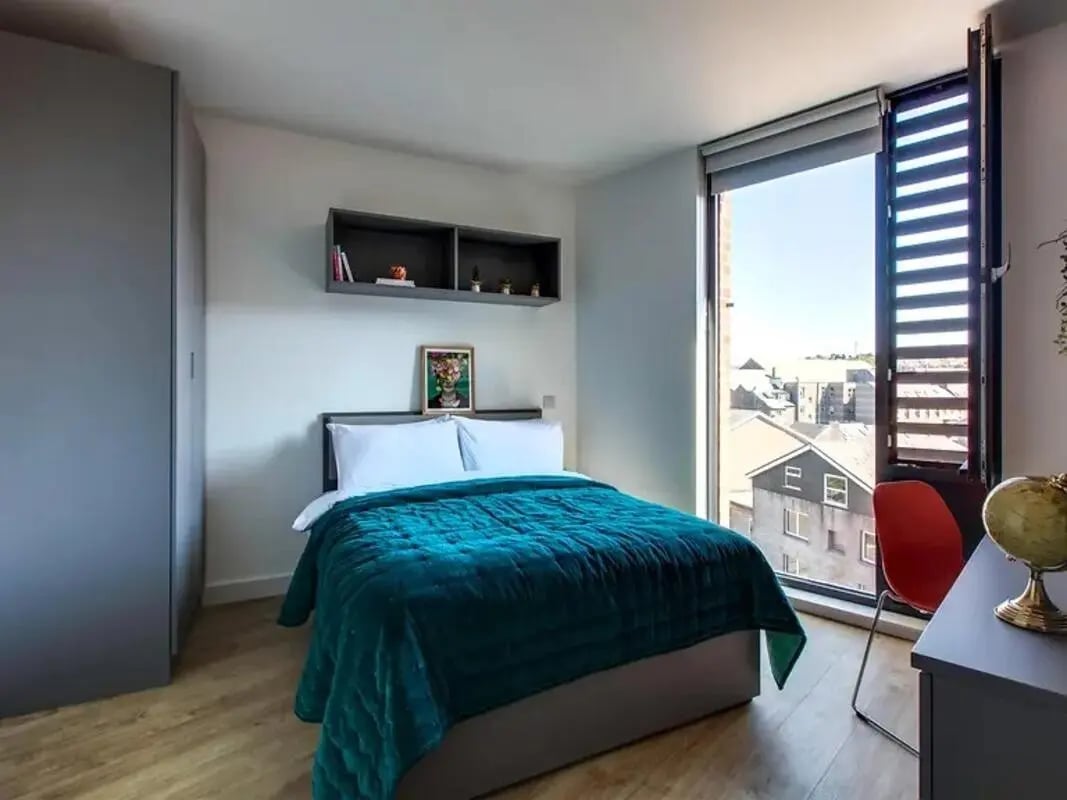 Bed with teal duvet shelves and large window bedroom at Lee Point in Cork Student Accommodation