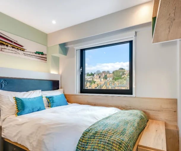 Bed with blue pillows and city view bedroom at Gravity in Lincoln Student Accommodation