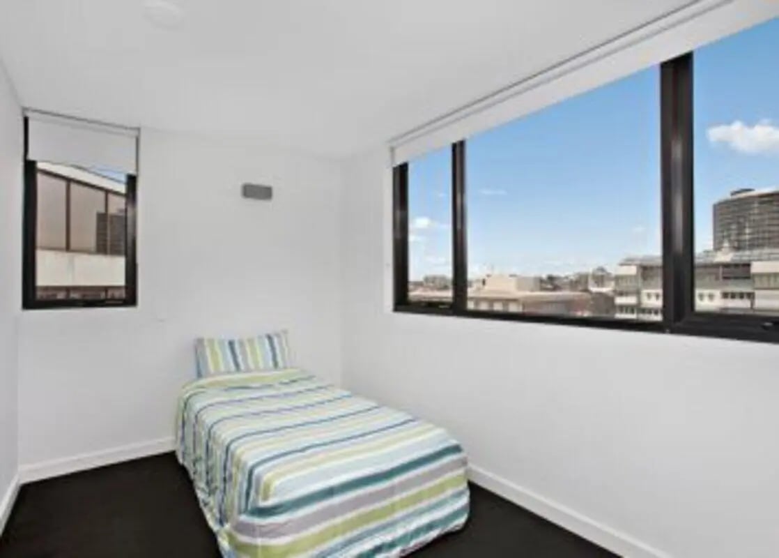 Single bed with striped bedding and city view bedroom at Student Living on Raleigh in Melbourne Student Accommodation