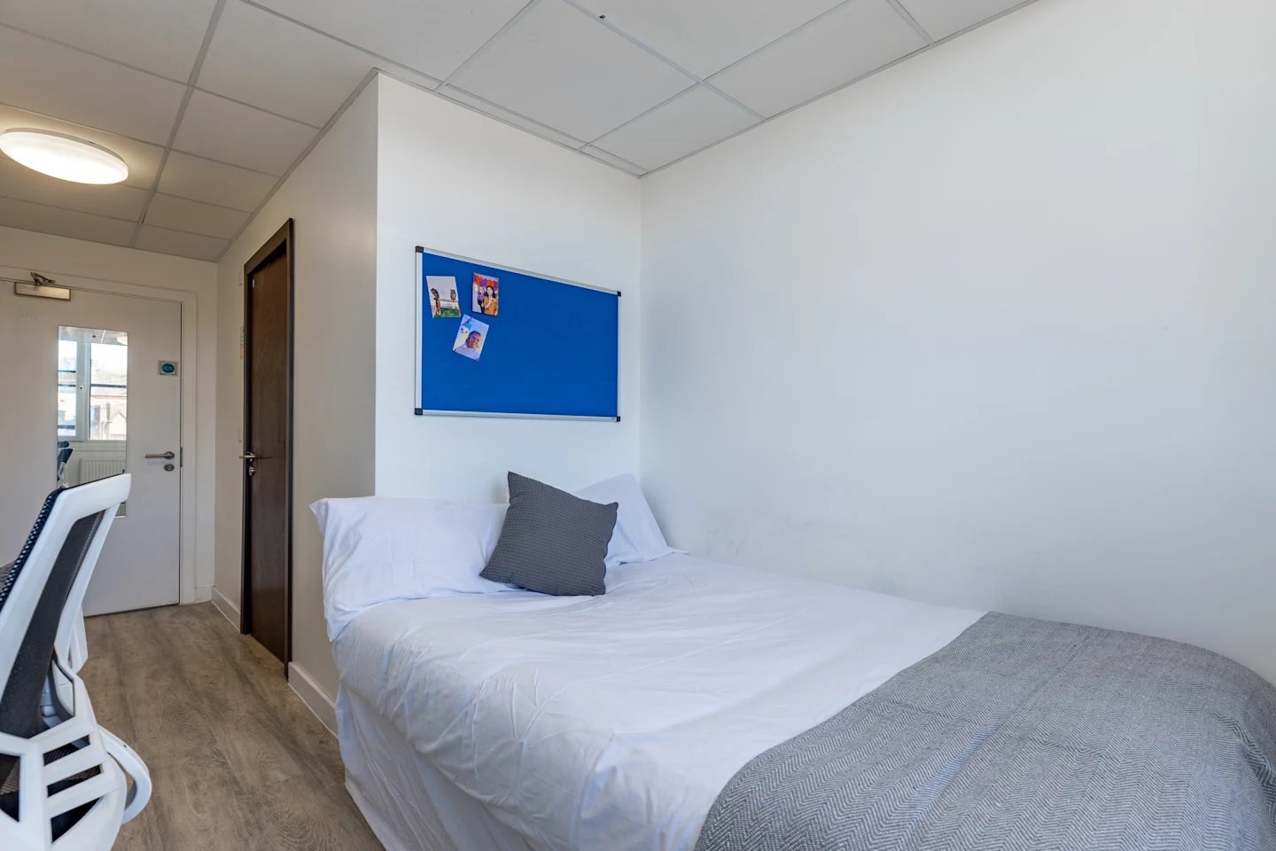 Bed with grey cushion and blue notice board bedroom at MyPad Paisley in Paisley Student Accommodation