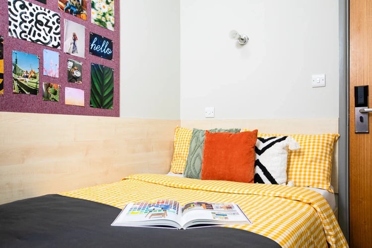 Bed with yellow checkered bedding colorful pillows open book Bedroom at The Rackhay in Bristol Student Accommodation