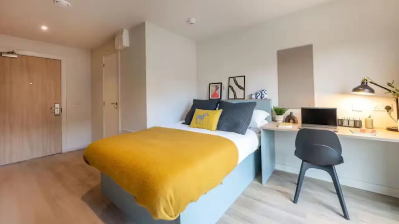 Bed with yellow throw desk with laptop study bedroom at Centre Court in Nottingham Student Accommodation