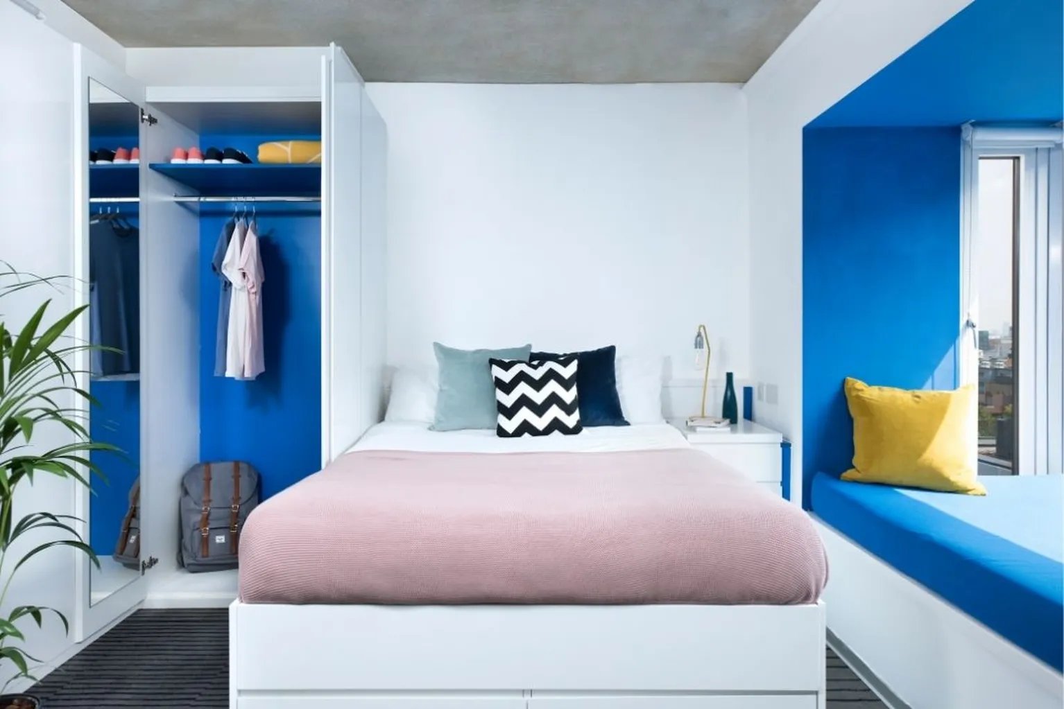 Bed with pink throw pillows and wardrobe bedroom at Scape Shoreditch in London Student Accommodation