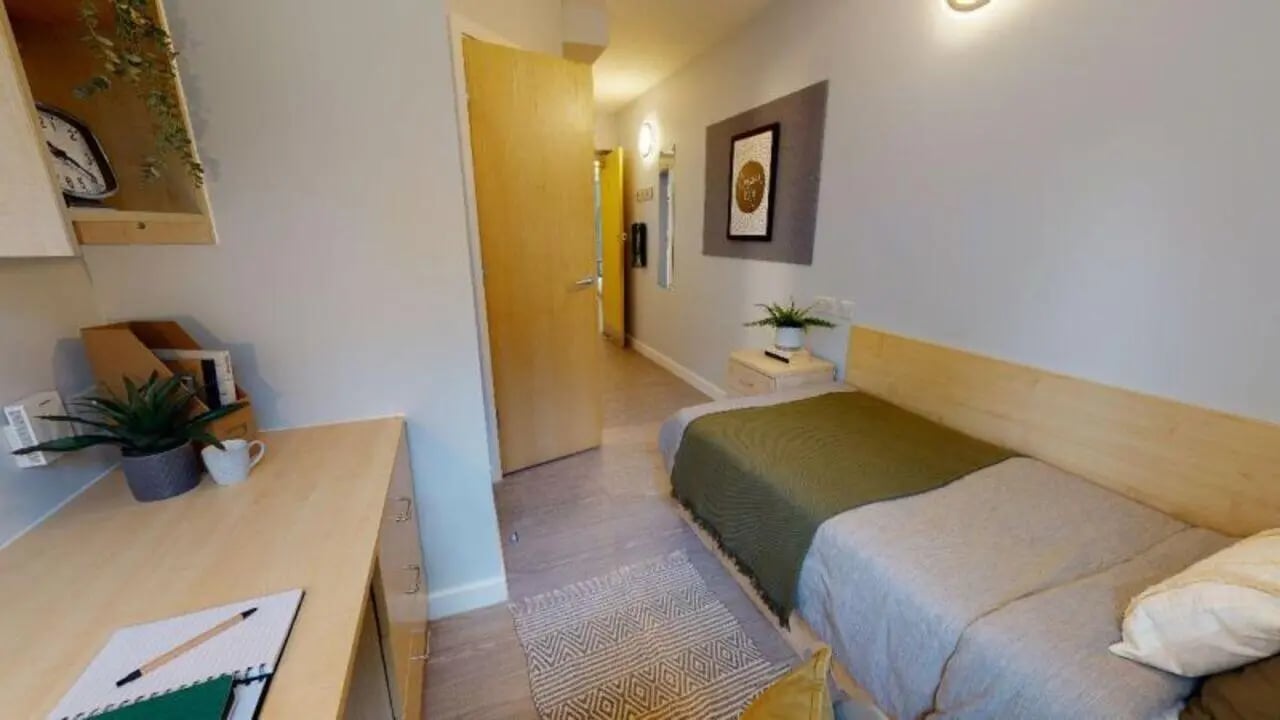 Bed desk plant and hallway bedroom at iQ Student Quarter in Salford Student Accommodation