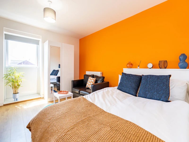 Bed with pillows couch mirror plant bedroom at The Rise Nottingham in Nottingham Student Accommodation