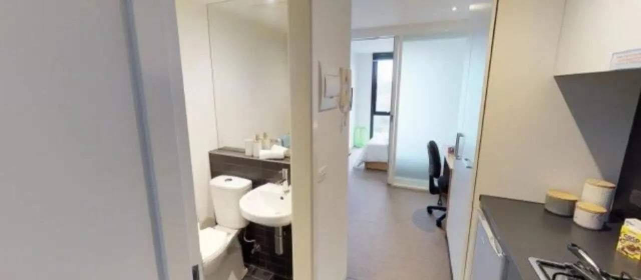 Toilet sink mirror desk chair and bed bedroom at Student Living on Villiers in Melbourne Student Accommodation