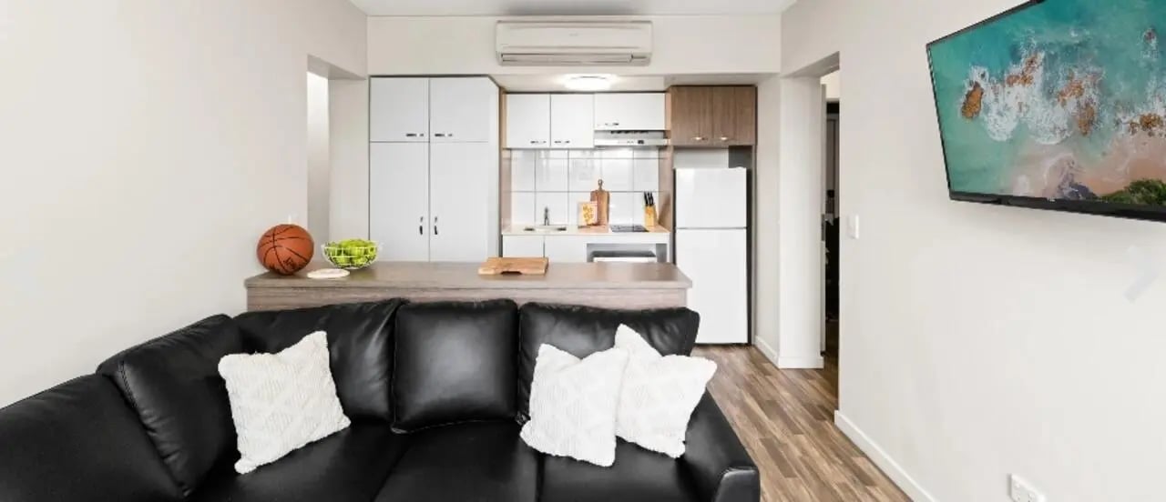 Black sofa kitchen area television living room at UniLodge Darwin in Darwin Student Accommodation