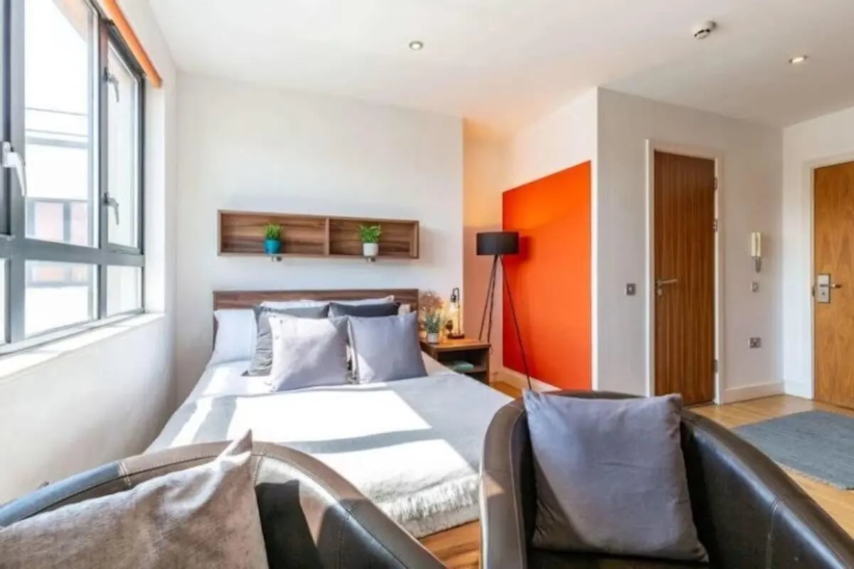 Bed with grey pillows and armchair bedroom at King Square Studios in Bristol Student Accommodation
