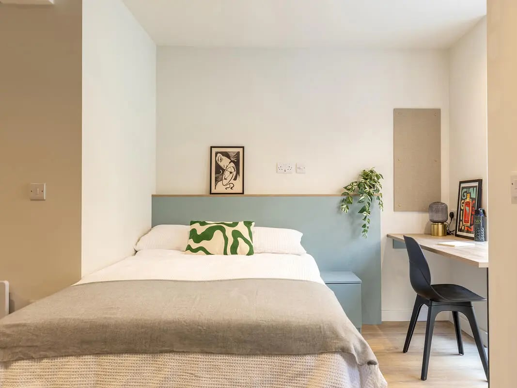 Bed with green pillow desk with chair bedroom at Centre Court in Nottingham Student Accommodation
