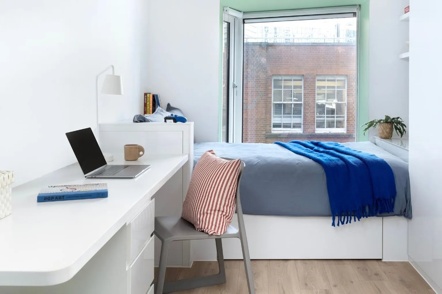 Bed desk laptop chair books pillow bedroom at Scape Shoreditch in London Student Accommodation