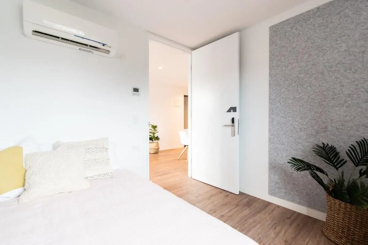 Bed with pillows air conditioner and open door bedroom at UniLodge Park Avenue in Melbourne Student Accommodation