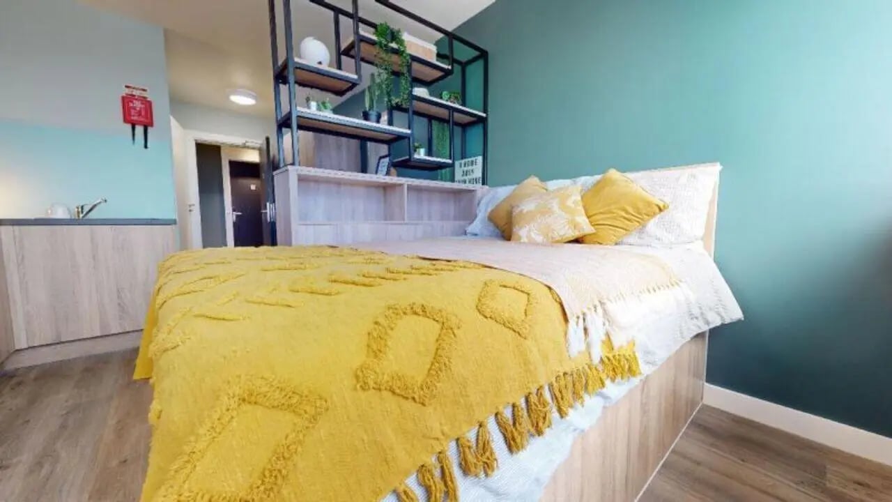 Bed with yellow throw and pillows bedroom area at Newtown House and Newland House in Nottingham Student Accommodation