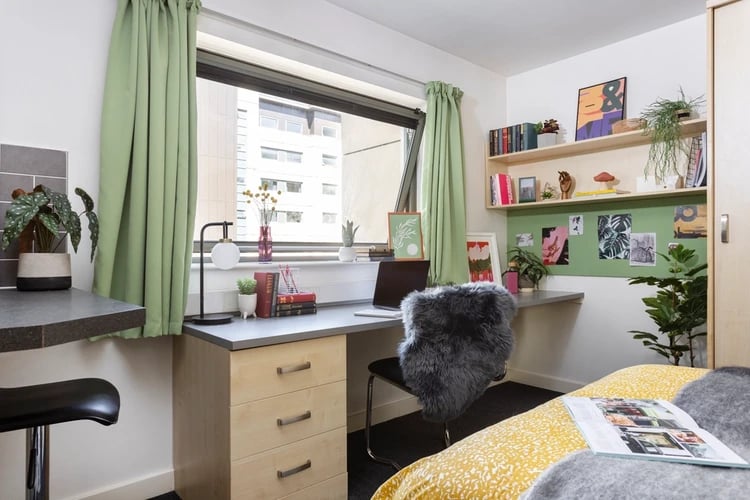 Desk lamp books laptop fluffy chair bedroom at Sir Charles Groves Hall in Manchester Student Accommodation