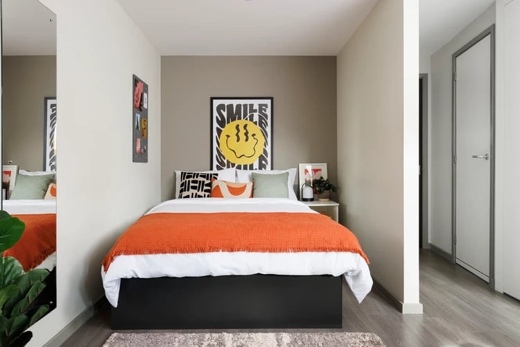 Bed with orange blanket and smiley poster Bedroom at Greetham Street in Portsmouth Student Accommodation