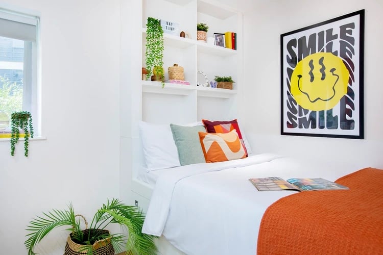 Bed with colorful pillows and smile poster Bedroom at Adam Street Gardens in Cardiff Student Accommodation