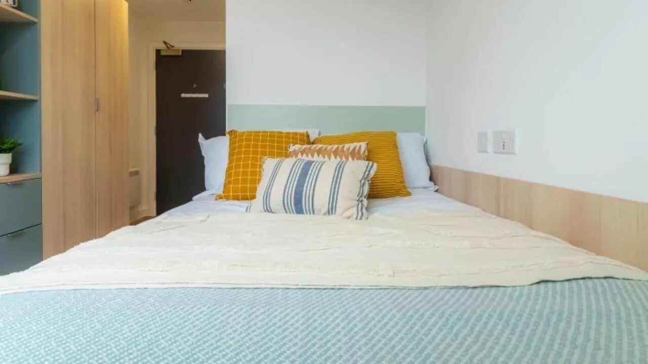 Bed with pillows wardrobe door and shelves bedroom at iQ Signal Place in Nottingham Student Accommodation