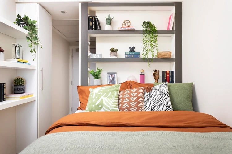 Bed with orange duvet and decorative pillows bedroom at Bridgewater Heights in Manchester Student Accommodation