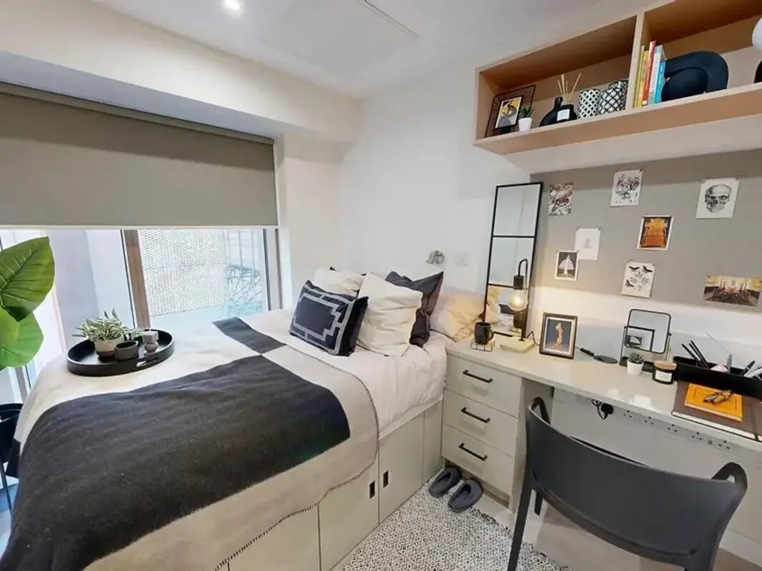 Bed desk shelf plants and pillows bedroom at Yugo Crown Place in Birmingham Student Accommodation