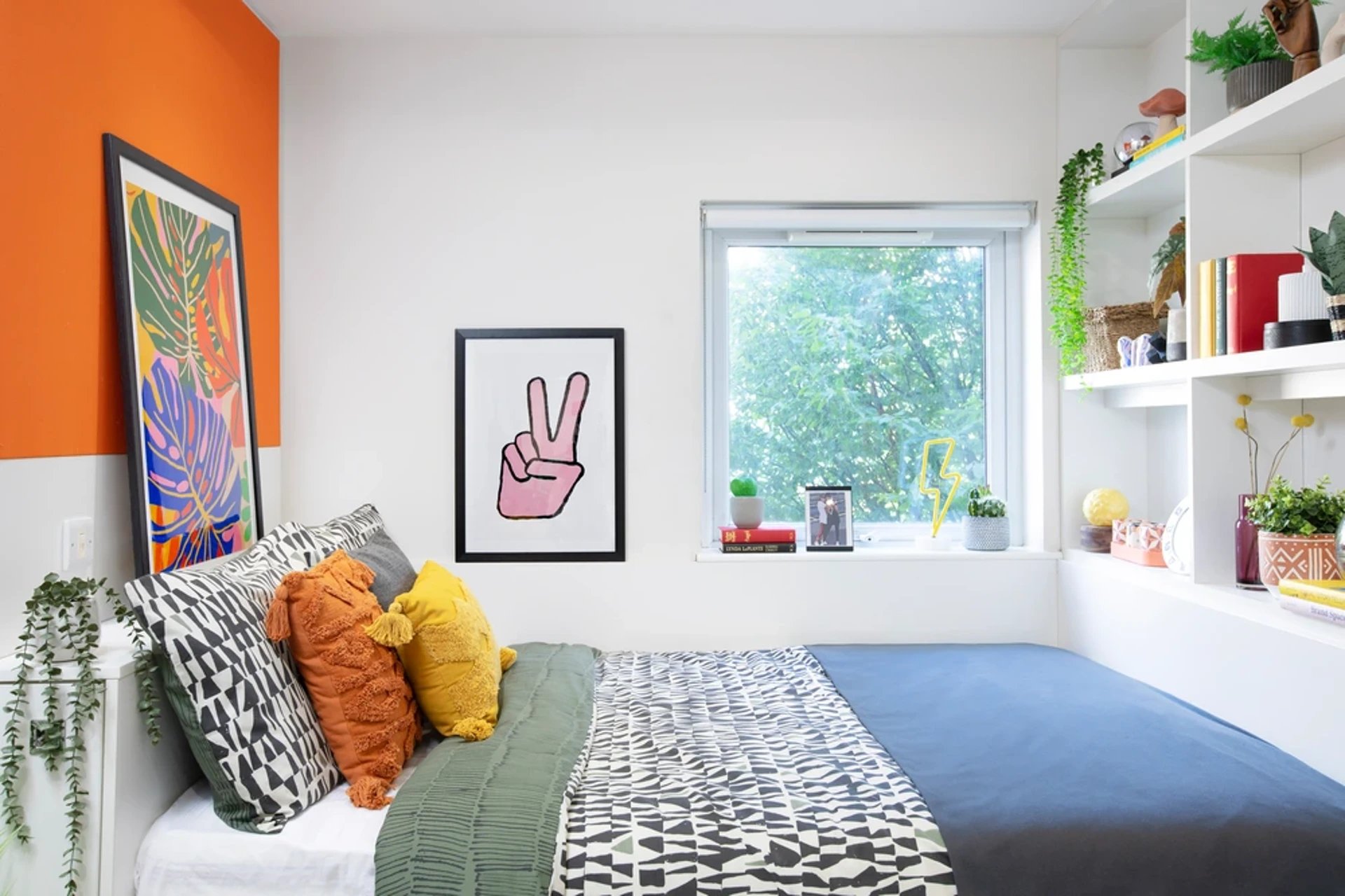 Bed with pillows artwork and shelves bedroom at Adam Street Gardens in Cardiff Student Accommodation