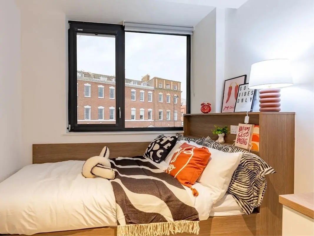 Bed with patterned blanket and pillows study area at Glassworks in Bristol Student Accommodation