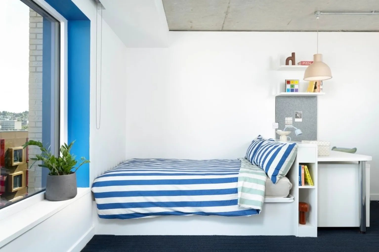 Striped bed desk plant and window bedroom at Scape Guildford in Guildford Student Accommodation