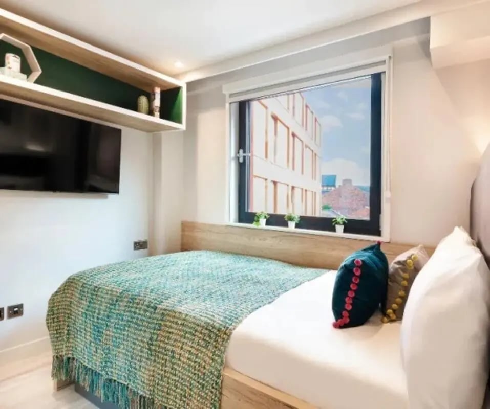 Bed with teal throw pillows and TV bedroom at Gravity in Lincoln Student Accommodation