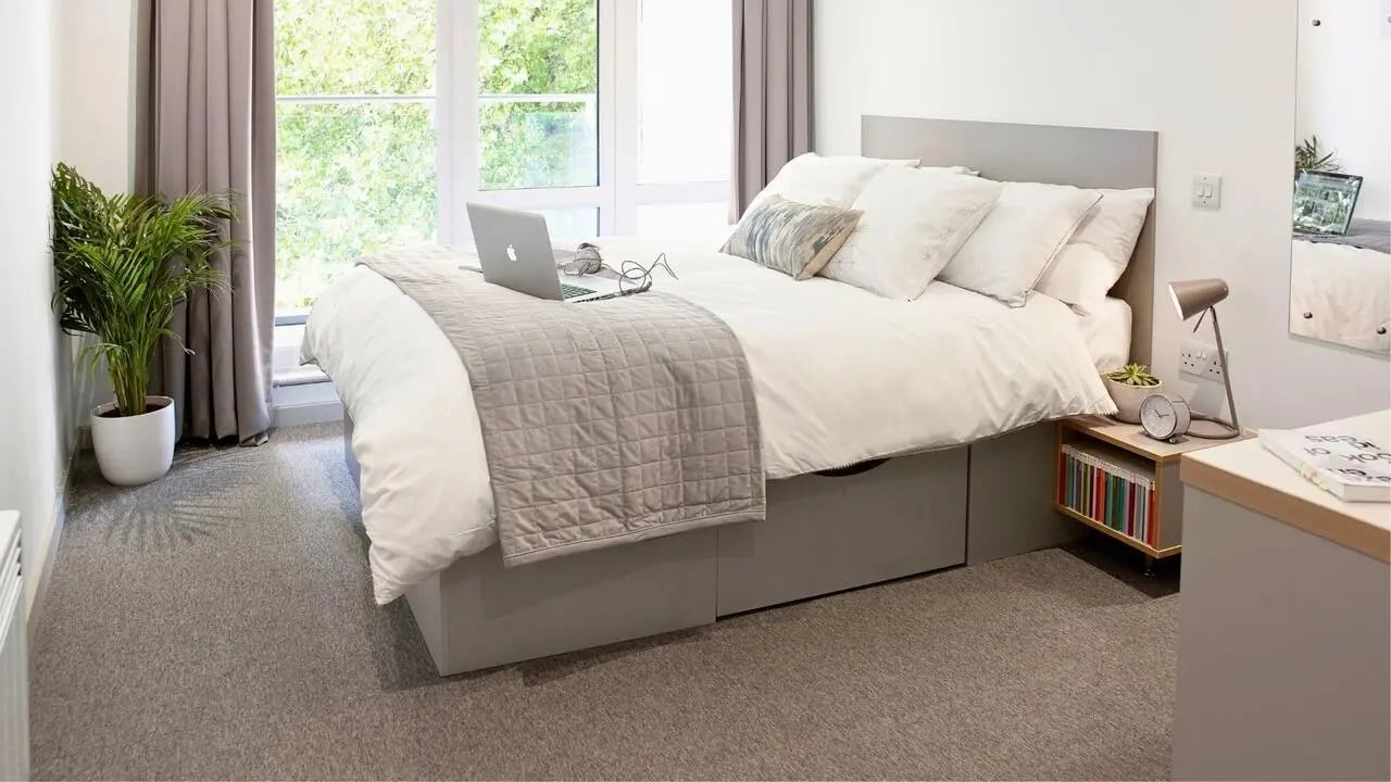 Bed with laptop plant and lamp bedroom at Lace Market Studios in Nottingham Student Accommodation