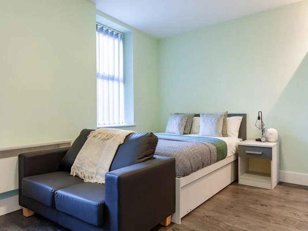 Sofa bed nightstand lamp with patterned bedding bedroom at Ty Ni in Bangor Student Accommodation