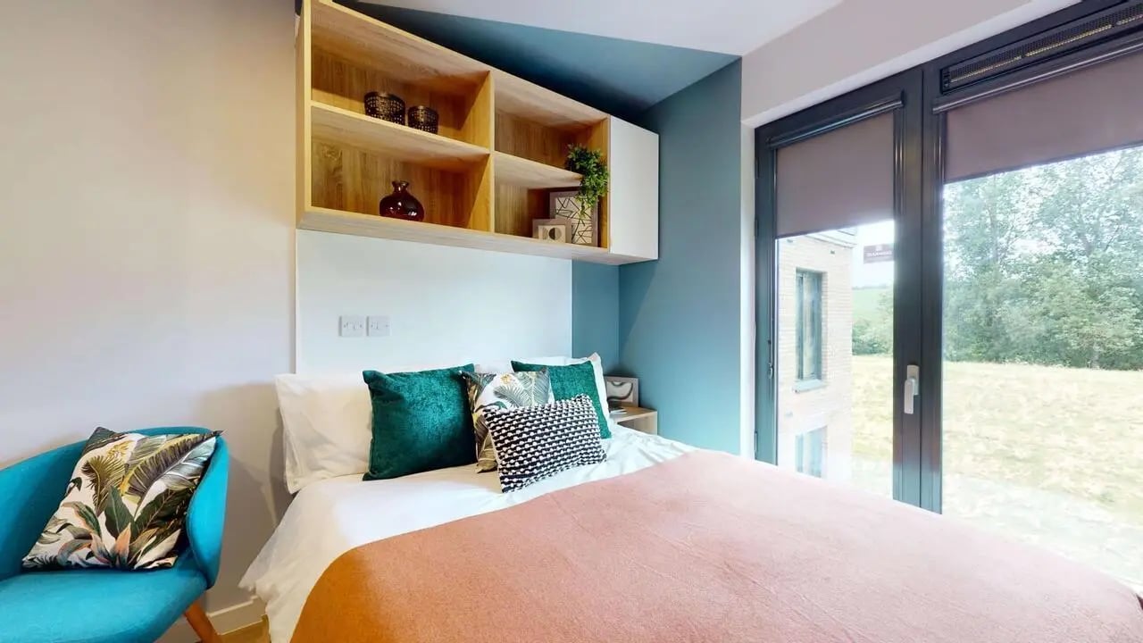 Bed with teal chair shelves and large window Bedroom at Mayfield Residences in Edinburgh Student Accommodation