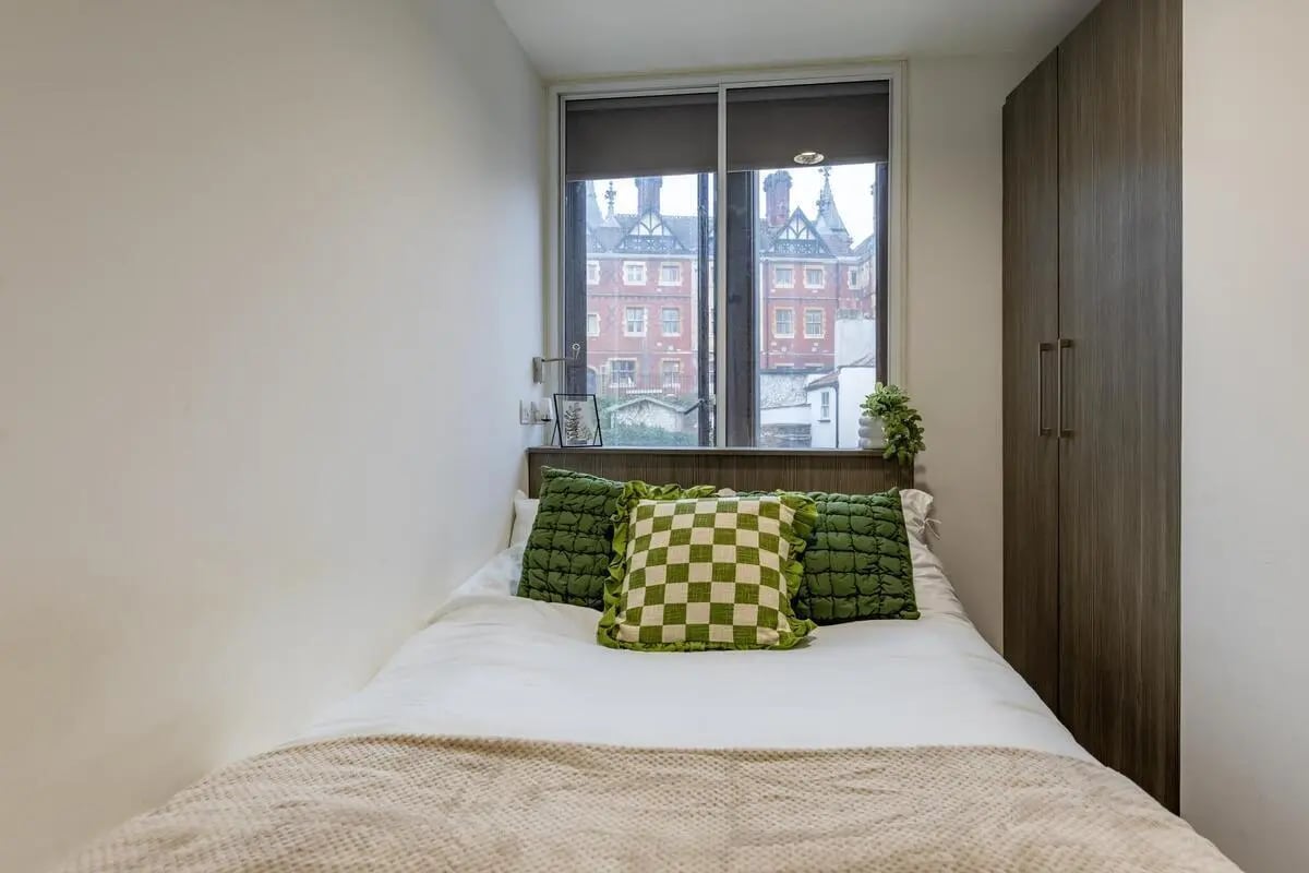 Bed with green pillows wardrobe and window bedroom at Centre Gate in Bristol Student Accommodation