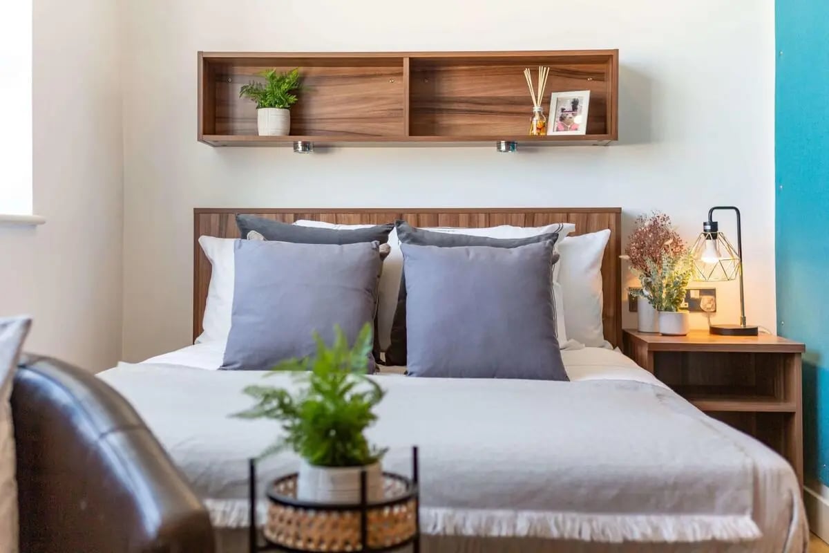 Bed pillows shelf plants and lamp bedroom at King Square Studios in Bristol Student Accommodation