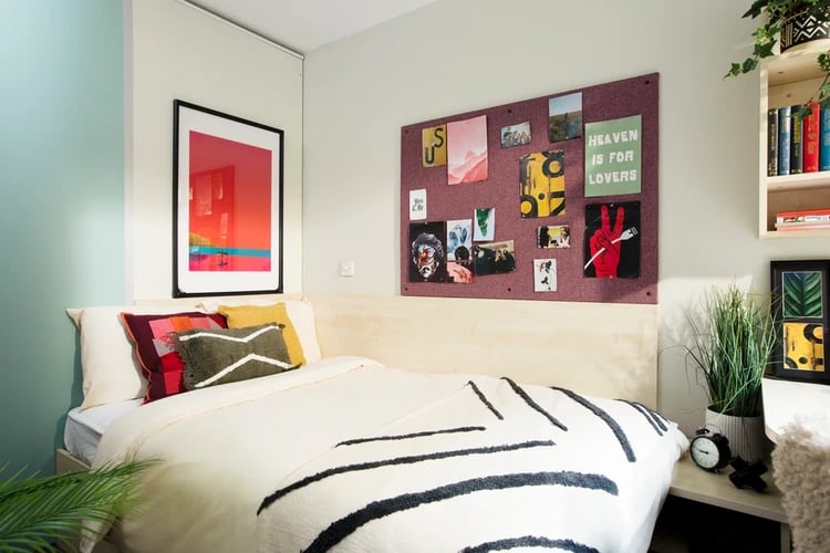 Bed with colorful pillows artwork and bulletin board bedroom at Blithehale Court in London Student Accommodation