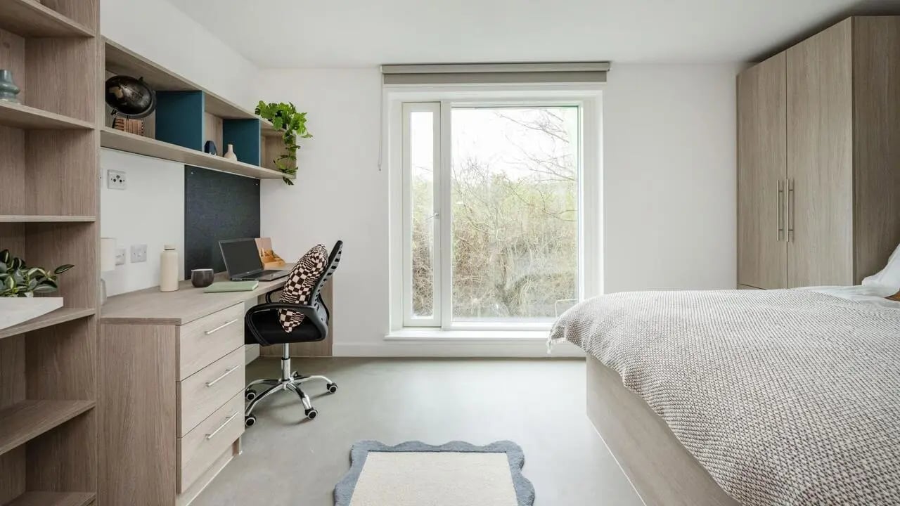 Desk shelves bed wardrobe window and rug bedroom at Timber Yard in Bristol Student Accommodation