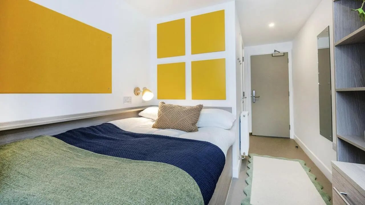 Bed with yellow wall panels and shelving bedroom at Timber Yard in Bristol Student Accommodation