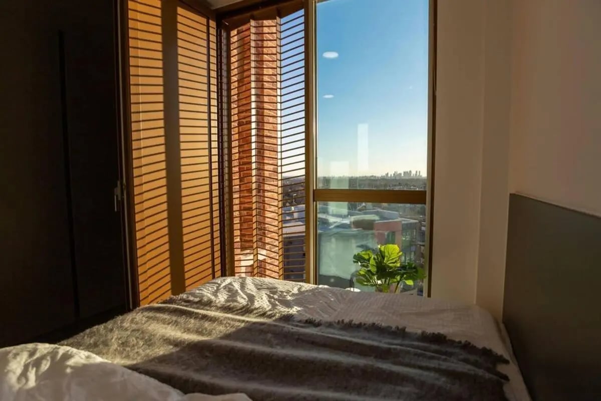 Bed with plant and city view bedroom at The Valentine London in London Student Accommodation