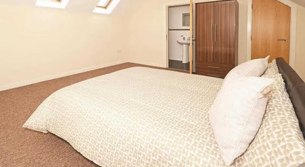 Bed with pillows wardrobe and sink ensuite bedroom at Hassells Bridge House in Newcastle Under Lyme Student Accommodation