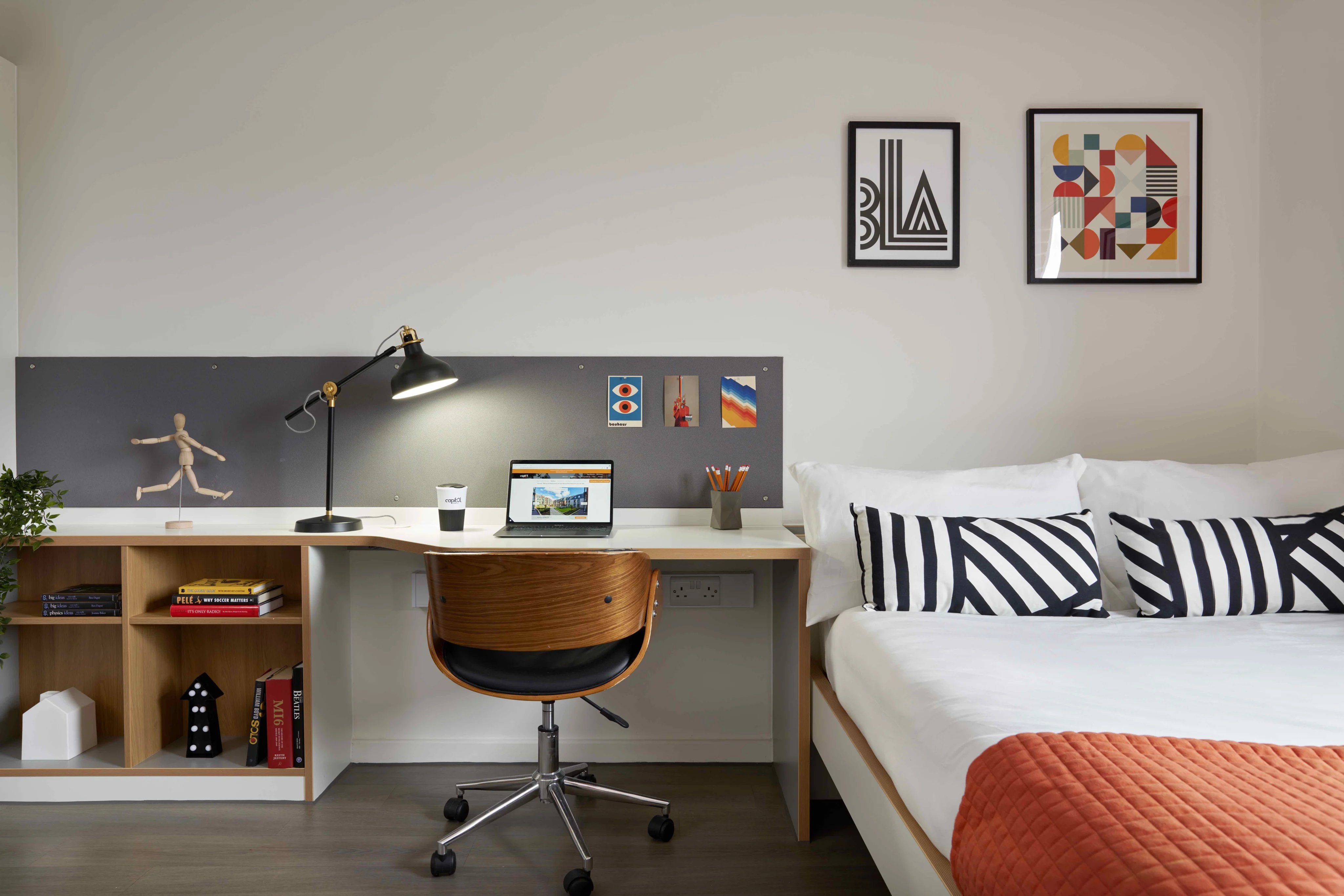 Desk bed lamp bookshelves and artwork bedroom at Asa Briggs House in Leeds Student Accommodation