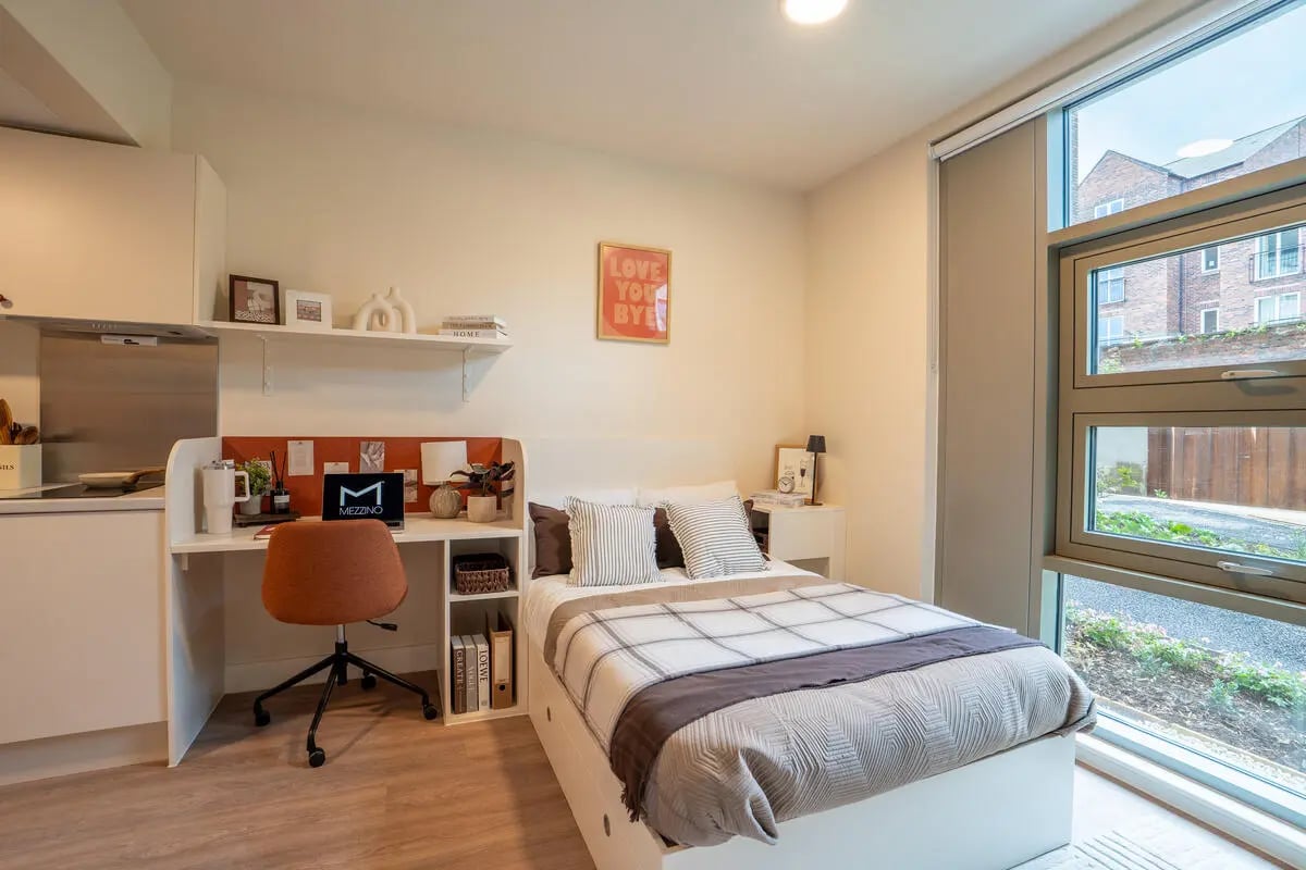 Bed desk chair laptop and kitchen area bedroom at Valerian in York Student Accommodation