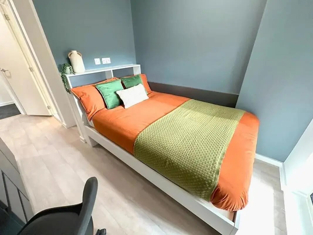 Bed with orange bedding green pillows bedroom at Enso in Colchester Student Accommodation