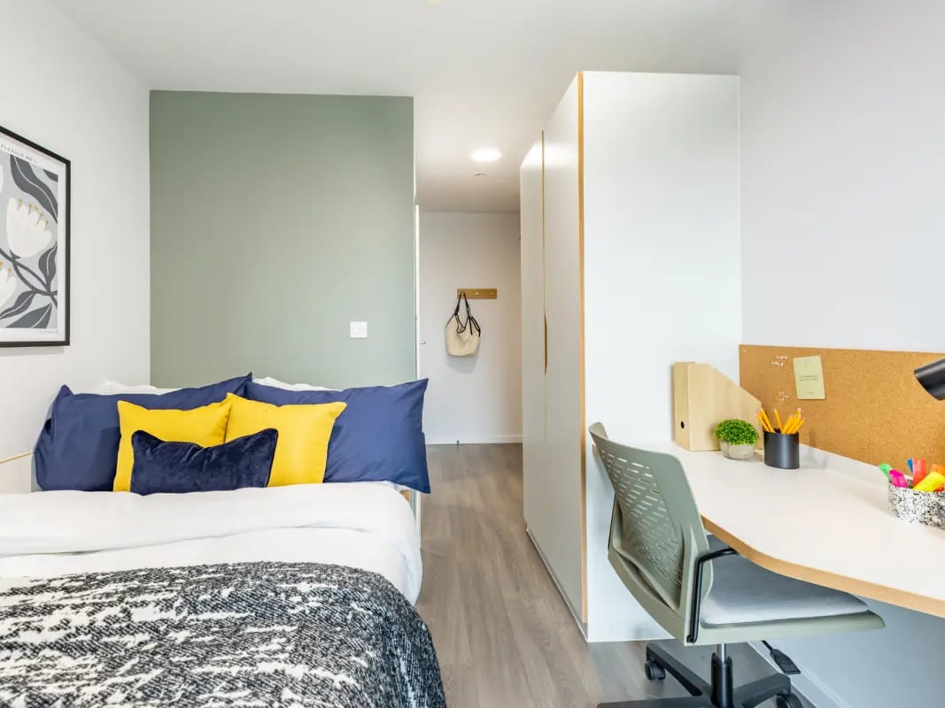 Bed with blue yellow pillows wardrobe desk study area bedroom at New Bridewell in Bristol Student Accommodation