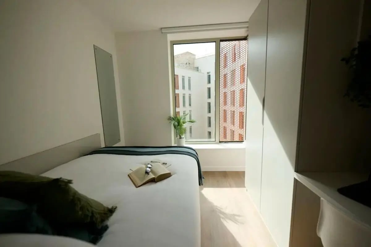 Bed with open book and plant bedroom interior at Brigg Point in Bristol Student Accommodation