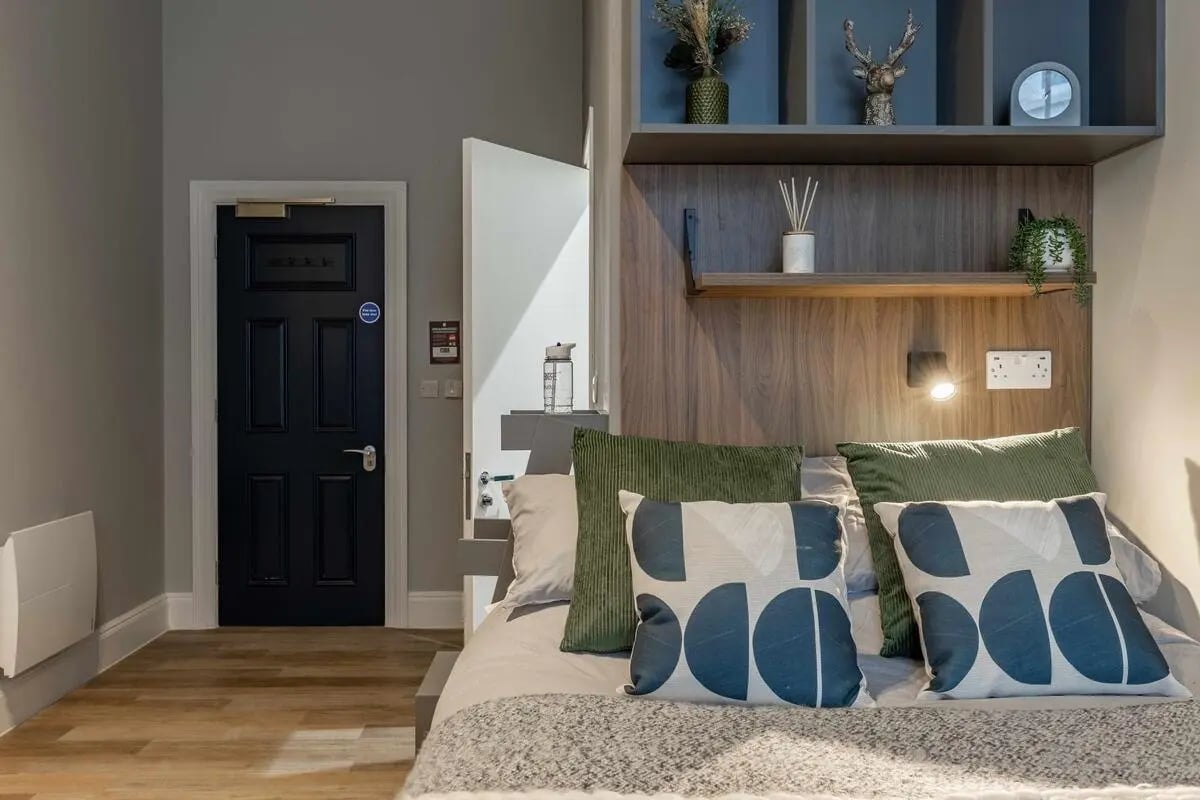 Bed with patterned pillows and shelves above bedroom at Chamberlain Place in Birmingham Student Accommodation