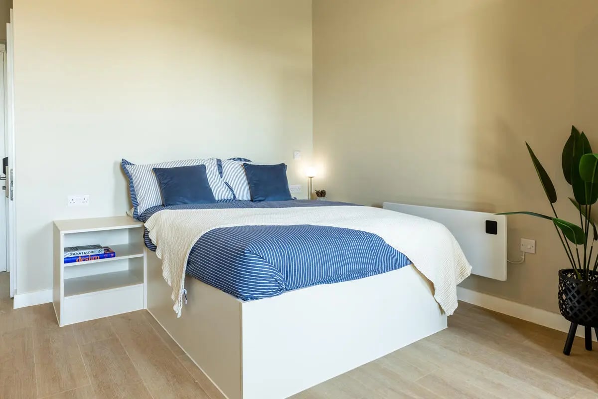 Bed with blue striped bedding and bedside table bedroom at Fitz and Knox in Cardiff Student Accommodation