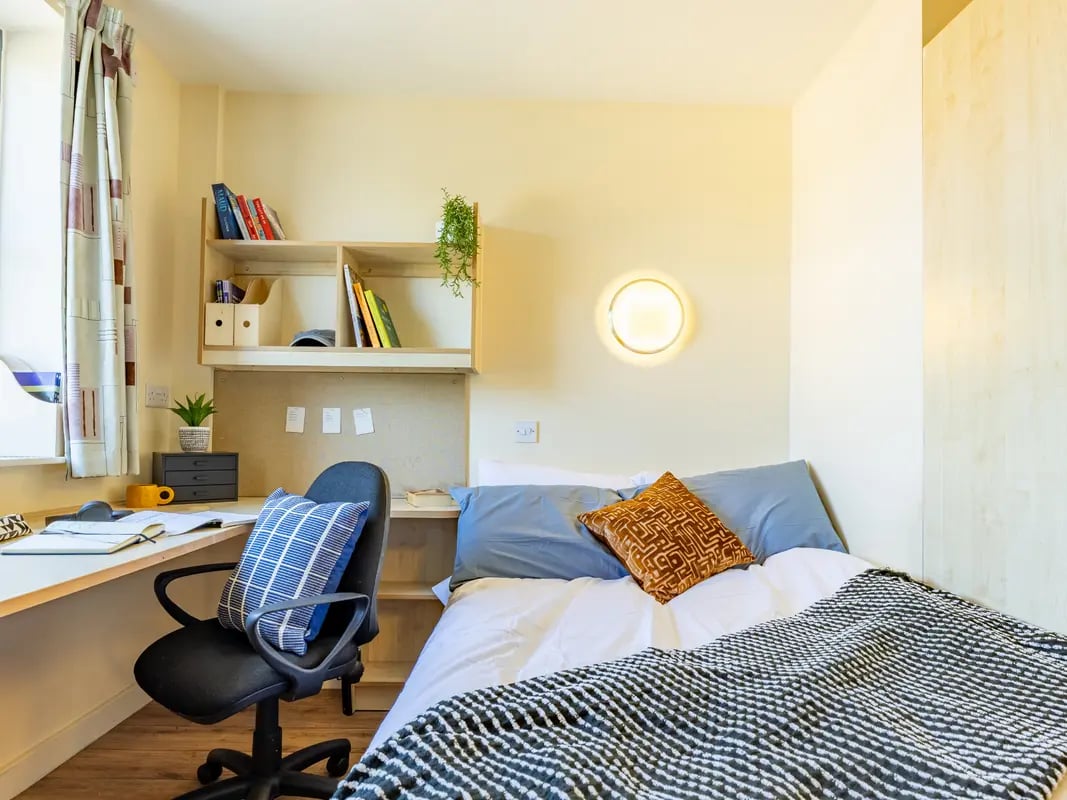Desk chair bed pillows shelves bedroom at Europa in Liverpool Student Accommodation