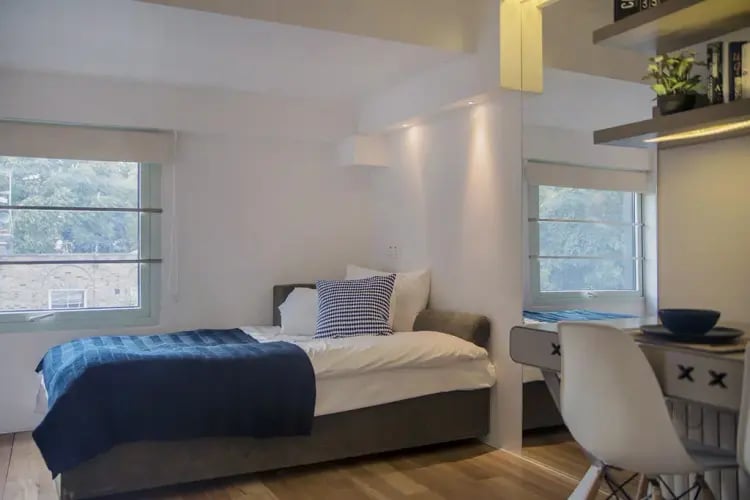 Bed with blue blanket and pillow study area at The Stay Club - Kentish Town in London Student Accommodation