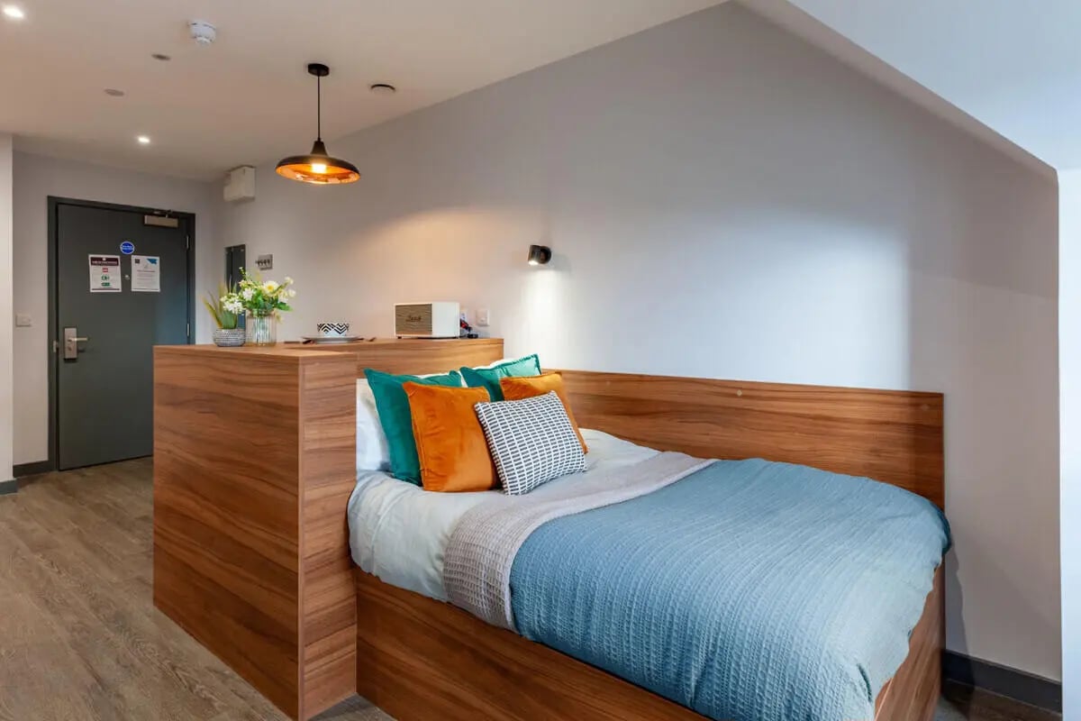 Bed with colorful pillows and wooden partition bedroom at Straits Garden in Egham Student Accommodation