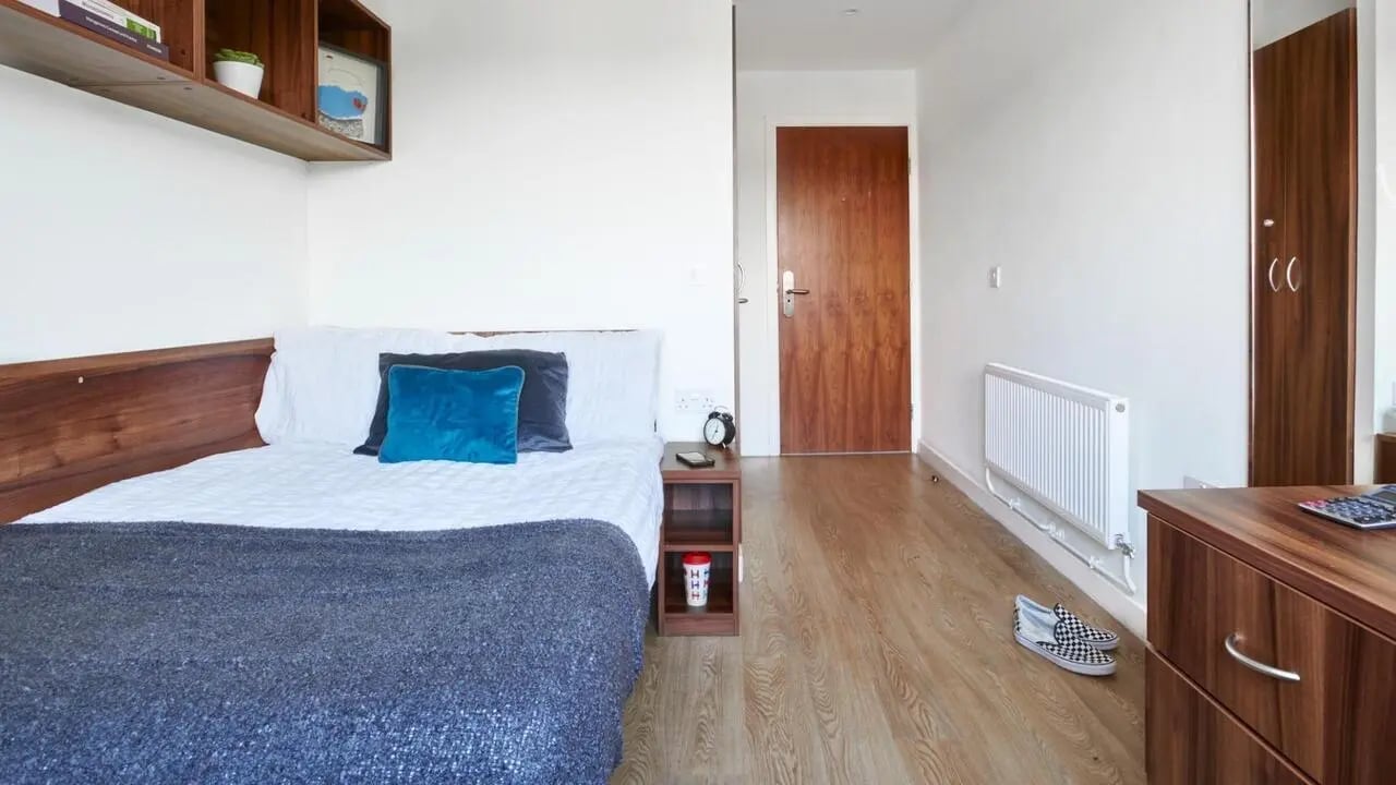 Bed with blue pillow bedside table radiator bedroom at The Printworks in Exeter Student Accommodation